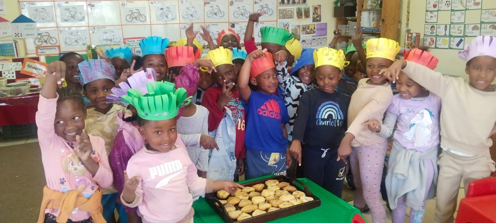 Smiling Kingsway children in paper chef hats with a tray of baking