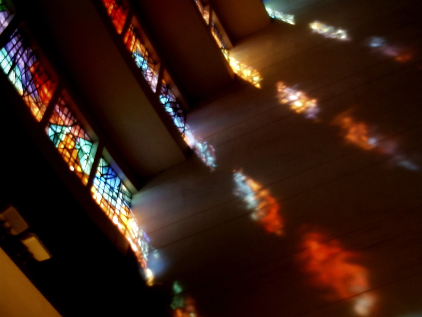 Light from stained glass windows falling across a church floor
